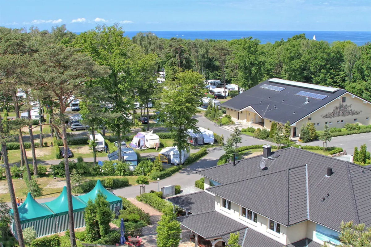 Camping.info Nº 1 en Alemania: camping Kühlungsborn. Puedes ver una vista aérea de un camping en el campo, con el mar al fondo.