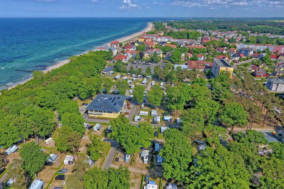 Camping.info Nº 1 en Alemania: camping Kühlungsborn. Puedes ver una vista aérea de un camping en el campo, con el mar al fondo.