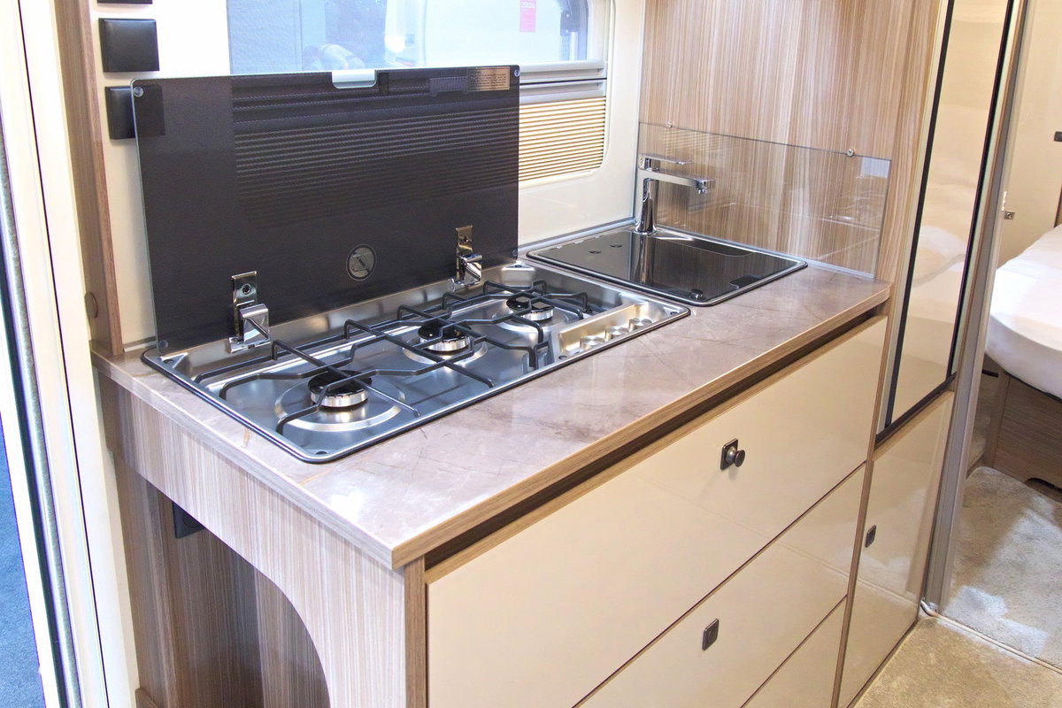 Fendt Tendenza 560 SFDW en el Caravan Salon 2026: bloque de cocina con placa de 3 fuegos, fregadero, frigorífico y espacio de almacenaje.
