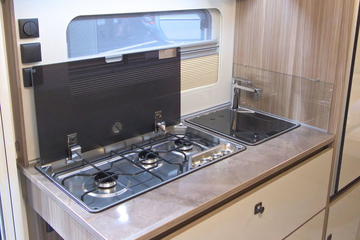 Fendt Tendenza 560 SFDW en el Caravan Salon 2026: bloque de cocina con placa de 3 fuegos y fregadero.